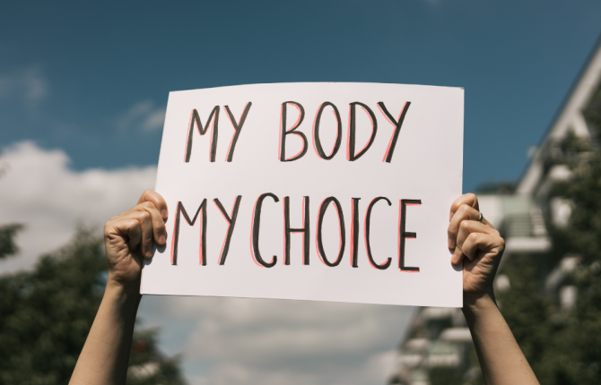 handen die een bord vasthouden met de tekst 'my body my choice'